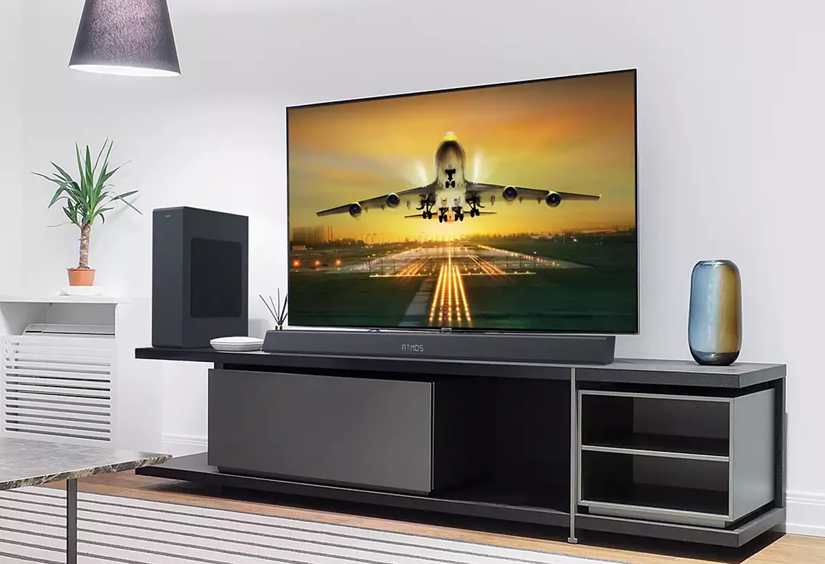 Απεικονίζεται το soundbar κάτω από τηλεόραση, η οποία προβάλλει κάποιο πρόγραμμα.